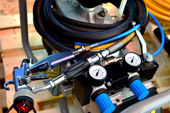 Professional pneumatic equipment, spray gun for painting or applying a waterproof polymer coating on cars, walls or other various surfaces. An analog indicator shows the level of air pressure. - Powered by Adobe