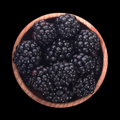 blackberry in wooden cup isolated on black background. top view
