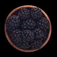 blackberry in wooden cup isolated on black background. top view