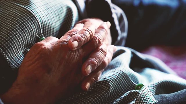 Detail of an ancient woman hands at home. She is crossing the fingers and shaking nervously. Hands of an old woman with life stories to tell. Respect and take care of old people.
