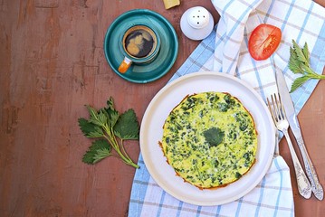 Breakfast, omelet with nettles on a white clay plate. Healthy food. Food from wild herbs. Top view, copy space. Italian food.
