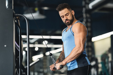 Muscular man pumping hands at gym interior