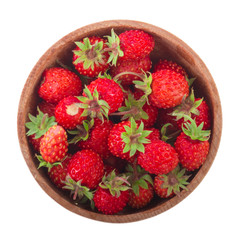 heap of red wild strawberries in wooden cup isolated on white background. top view