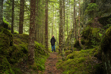 Man with hat and jacket standing in a forest clearing. Oslo, Norway.
