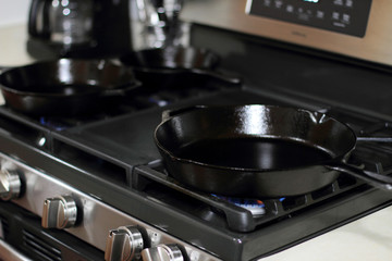 Cast iron skillets heating up on a natural gas stove.