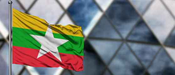 Myanmar flag waving in the wind against blurred modern building. Business concept. National...