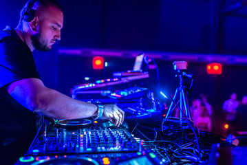 DJ Playing House and Techno Music in a Night Club. Mixing and Controlling the Music.