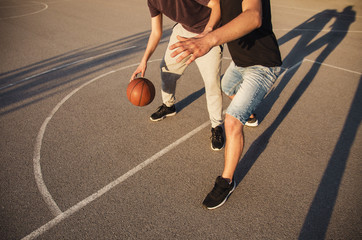 Naklejka premium Unrecognizable young people playing basketball , sunset 
