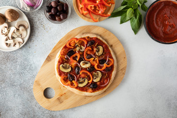 Top view of vegetarian pizza with mushrooms, olives and sweet pepper on a light background