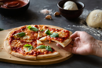 Ingredients for traditional Italian pizza Margherita with tomato sauce, Mozzarella cheese, basil on a dark concrete background. Pizza recipe and menu.