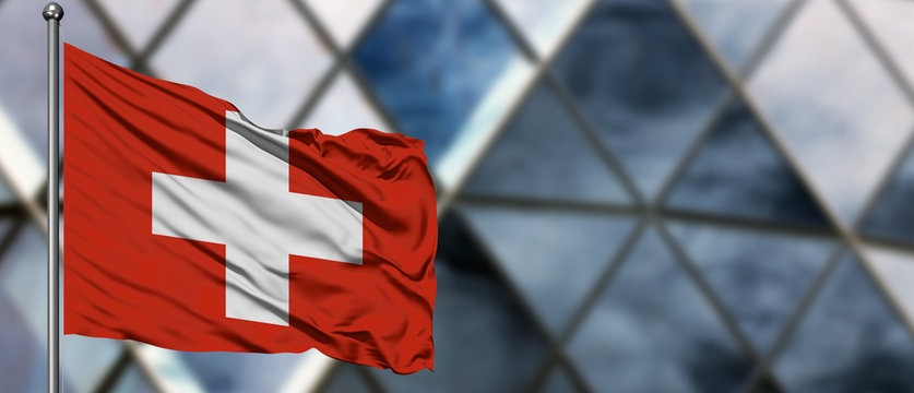 Switzerland flag waving in the wind against blurred modern building. Business concept. National cooperation theme.