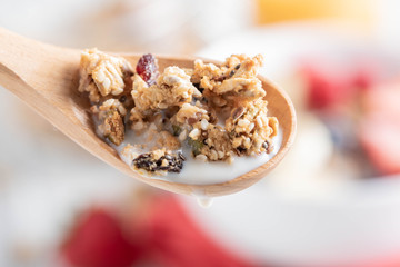 granola and milk in wooden spoon