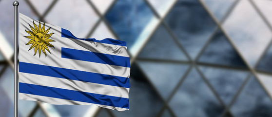 Uruguay flag waving in the wind against blurred modern building. Business concept. National...