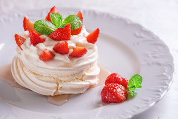 Pavlova dessert with strawberries on a white plate.