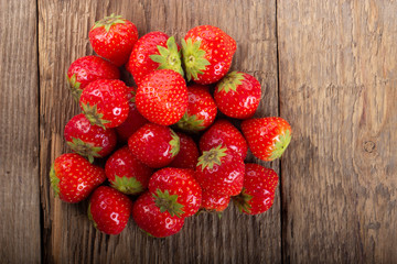heap of strawberries on wooden background. top view
