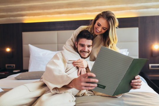 Couple In Hotel Room Reading Room Service Menu Together In Bed