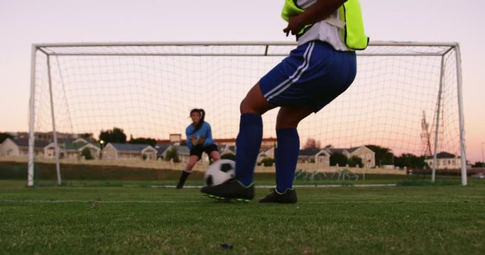 Female keeper waiting for female soccer player to shoot the ball.