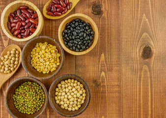 Flat lay,top view assorted beans including red bean,soybeans,black beans,mung beans on brown,beige wooden background with copy space 