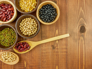 Flat lay,top view assorted beans including red bean,soybeans,black beans,mung beans on brown,beige wooden background with copy space 