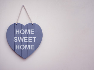 Heart shape wooden sign hanging on a wall, Home sweet home is written on the sign, Copy space, Toned.