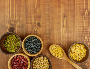 Flat lay,top view assorted beans including red bean,soybeans,black beans,mung beans on brown,beige wooden background with copy space 