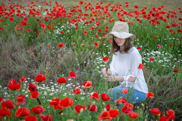 beautiful young woman in a flower field with hat 