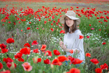 beautiful young woman in a flower field with hat 