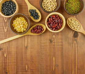 Flat lay,top view assorted beans including red bean,soybeans,black beans,mung beans on brown,beige wooden background with copy space 
