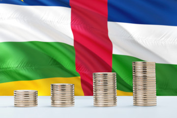 Central African Republic flag waving in the background with rows of coins for finance and business concept. Saving money.