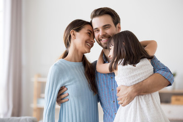 Naklejka premium Happy man hug beautiful wife and daughter in living room
