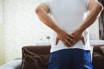 unhappy man suffering from backache at home.  discus hernia