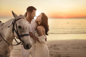 Poster Im Rahmen Junges Paar, das auf einem majestätischen Pferd spazieren geht - Küstenlandschaft © konradbak