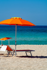 Service on beach, colorful sun bed and parasol for rent on beautiful white sandy beach with crystal clear blue sea water © barmalini