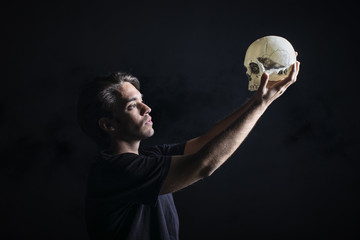 Actor con calavera interpretando la obra de teatro Hamlet de Shakespeare - obrazy, fototapety, plakaty