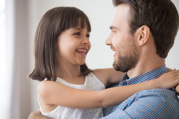 Smiling dad hold daughter in arms laughing together