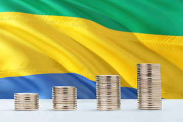 Gabon flag waving in the background with rows of coins for finance and business concept. Saving...