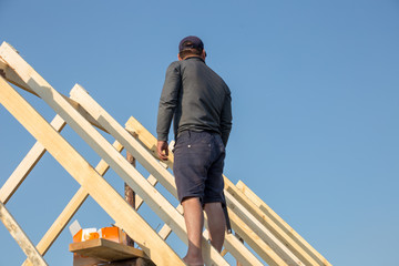 Roofer, carpenter on the roof, he closes the roof of a small and cozy house