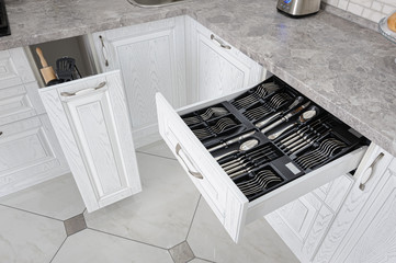 drawer with silver cutlery in modern white kitchen
