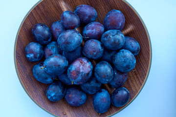 Fresh ripe plums on the wooden bowl