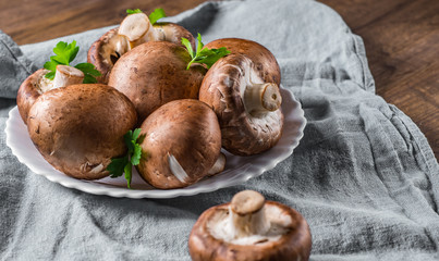 Group of whole raw fresh brown mushroom portobello on white plate. 