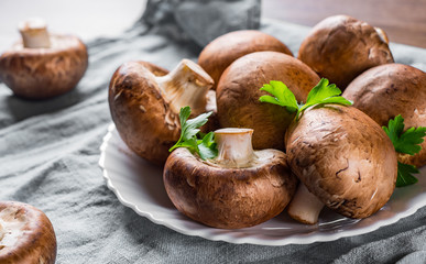 Group of whole raw fresh brown mushroom portobello on white plate. 