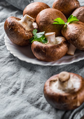 Group of whole raw fresh brown mushroom portobello on white plate. 