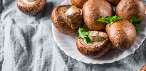 Group of whole raw fresh brown mushroom portobello on white plate. 