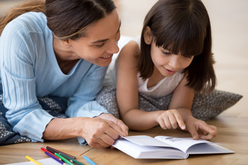 Caring mom reading interesting book with small daughter