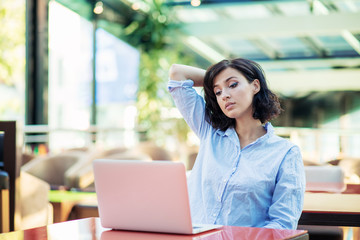 young and beautiful girl with notebook and laptop sitting in a cafe