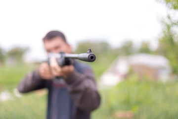 Young man shoots air rifle in nature
