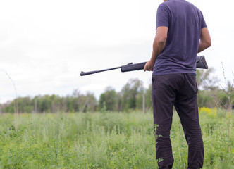 Young man shoots air rifle in nature