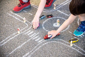 Two brothers sibling kid boy having fun with picture drawing traffic car with chalks. Creative leisure for children outdoors in summer. Difficult traffic rules education friendship concept