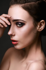 Fototapeta na wymiar Beautiful brunette with bright make-up smoky eyes, thick eyebrows, pink lips. Evening look