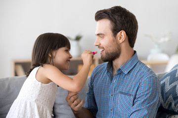 Funny little girl do makeup paint lips for young dad
